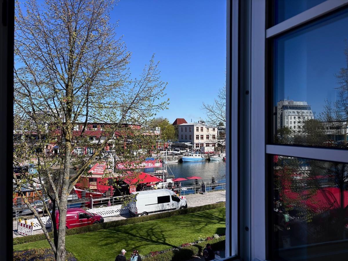 Blick aus dem Fenster auf Hafen mit Booten und roten Markisen.