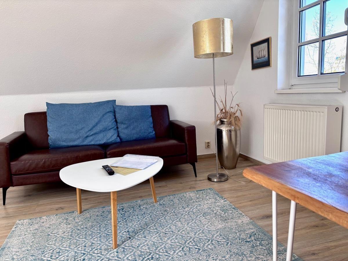Ein Wohnzimmer mit braunem Sofa, blauen Kissen, runder Tisch und Teppich.