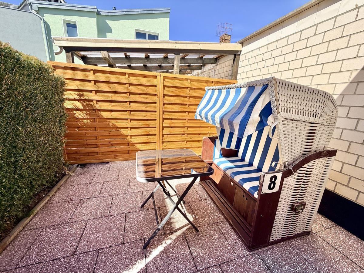 Terrasse mit Liegestuhl und Tisch. Holzgeländer und Steinplatten.