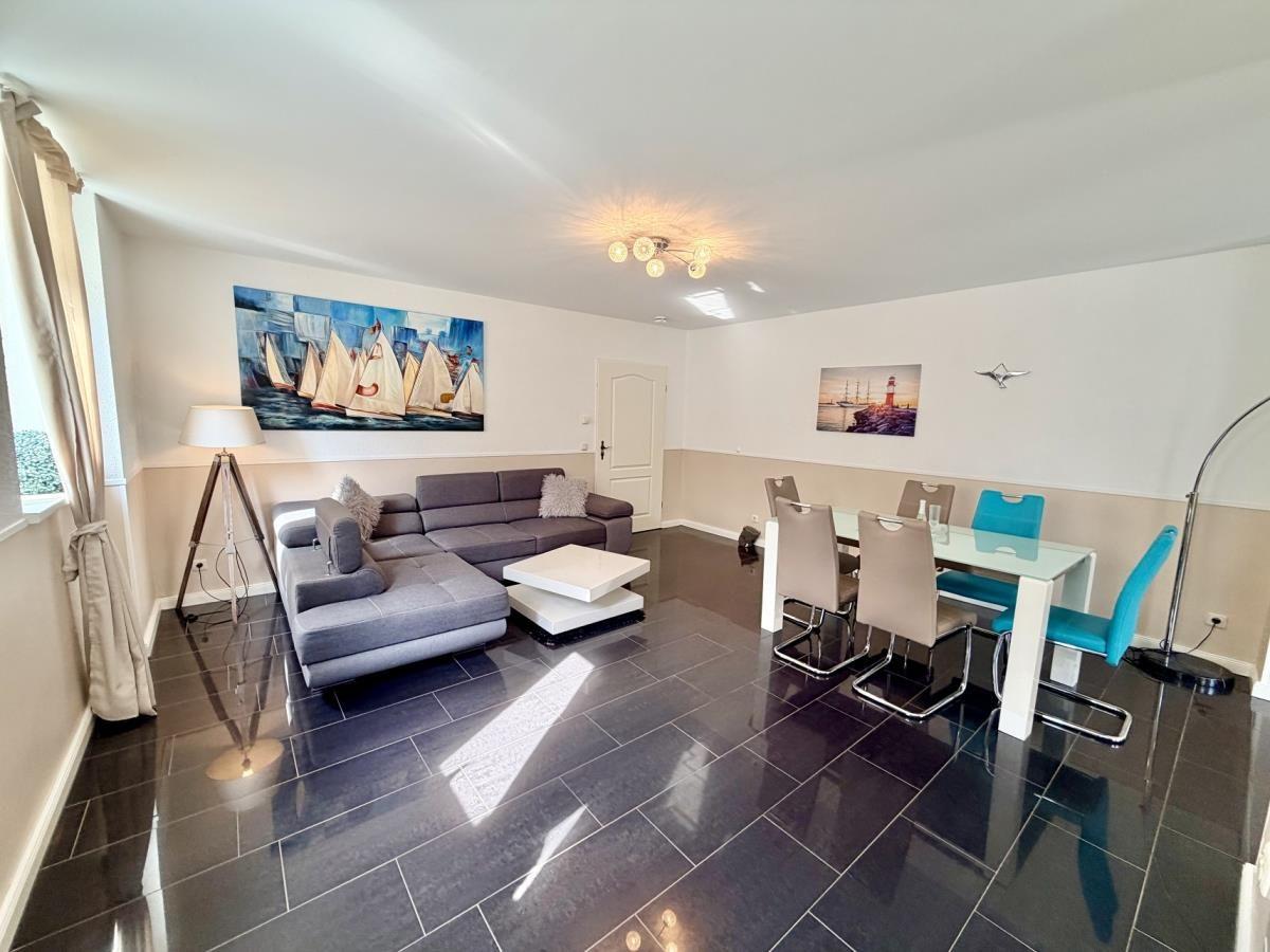 Wohn- und Essbereich mit Sofa, Tisch und Stühlen sowie Wandbildern.