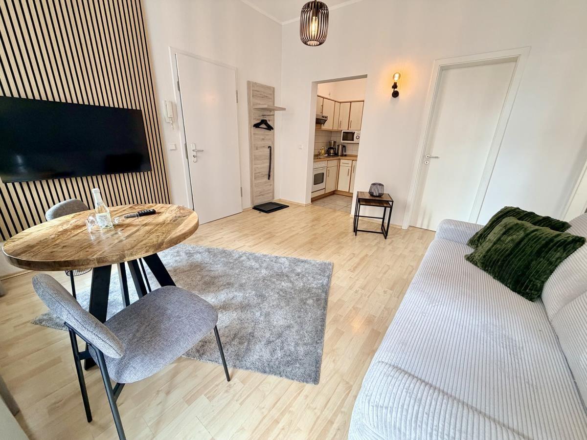 Wohnbereich mit Sofa, Esstisch und Küchenbereich im Hintergrund.