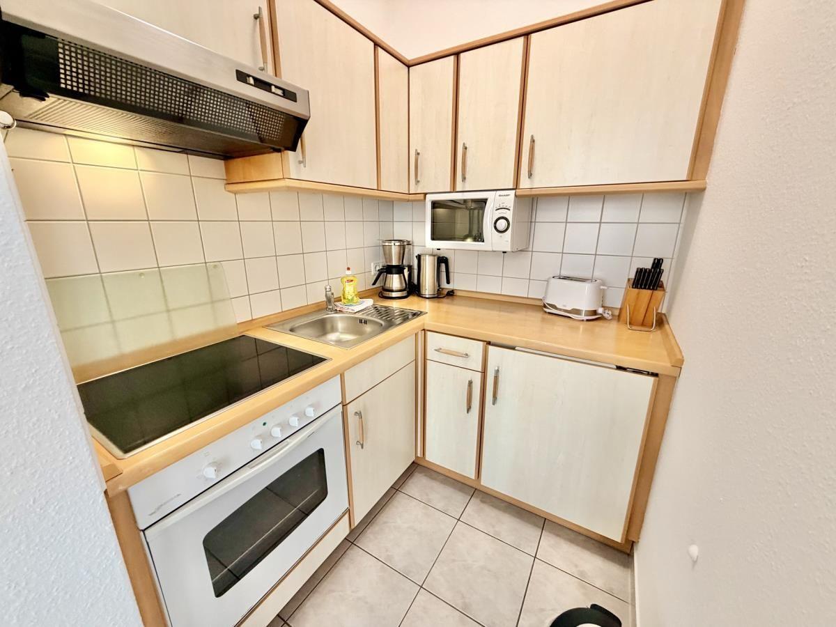 Küche mit Holzschränken, Herd, Spüle und Mikrowelle.