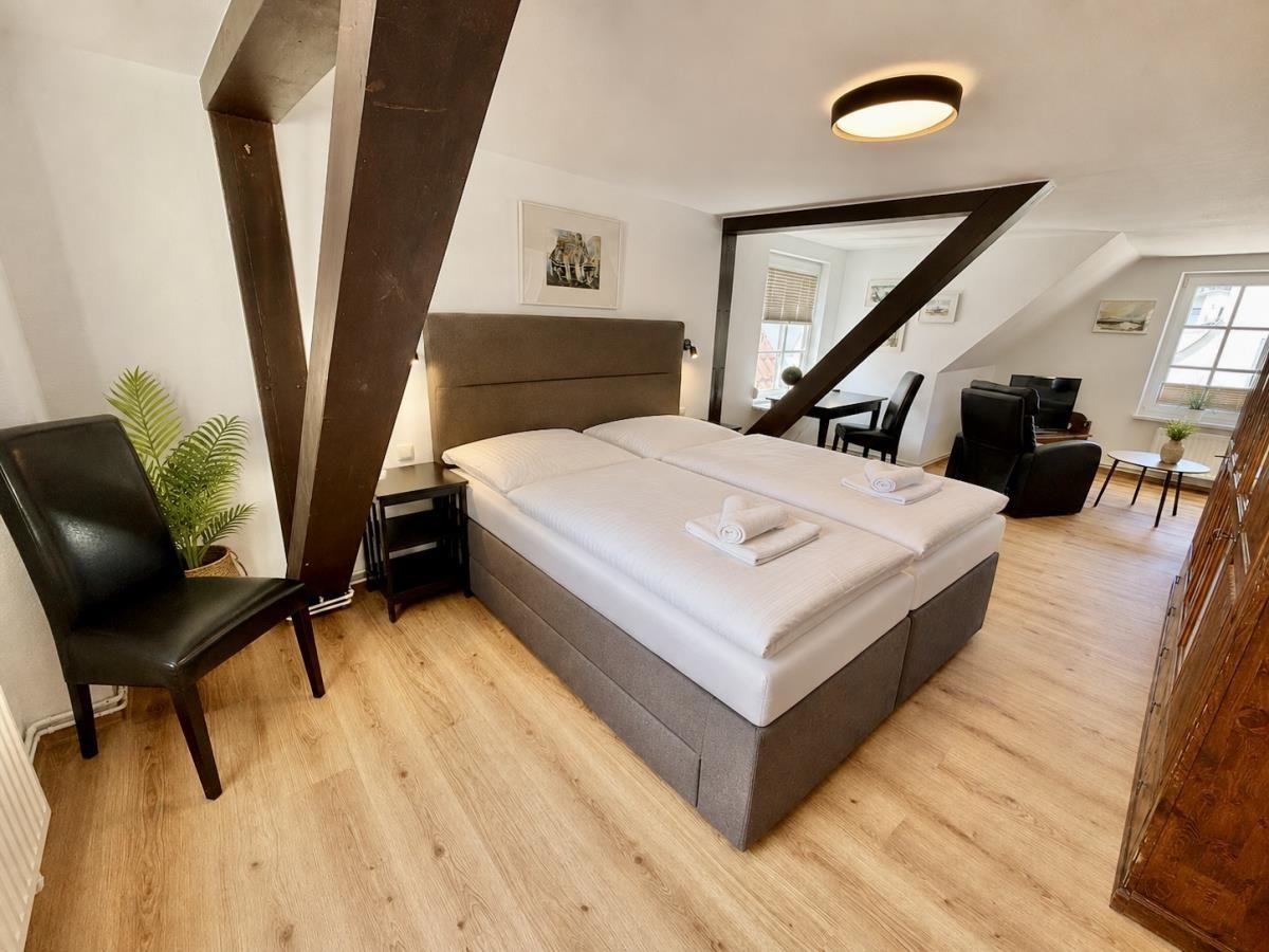 Schlafzimmer mit Doppelbett, Holzboden und Sicht auf Wohnbereich.