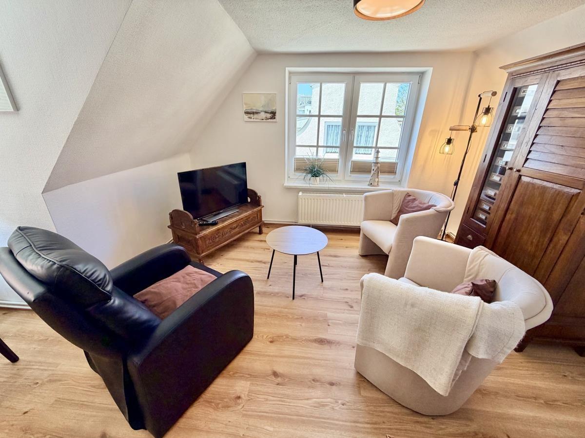 Wohnzimmer mit zwei Sesseln, Fernseher und Holzboden.