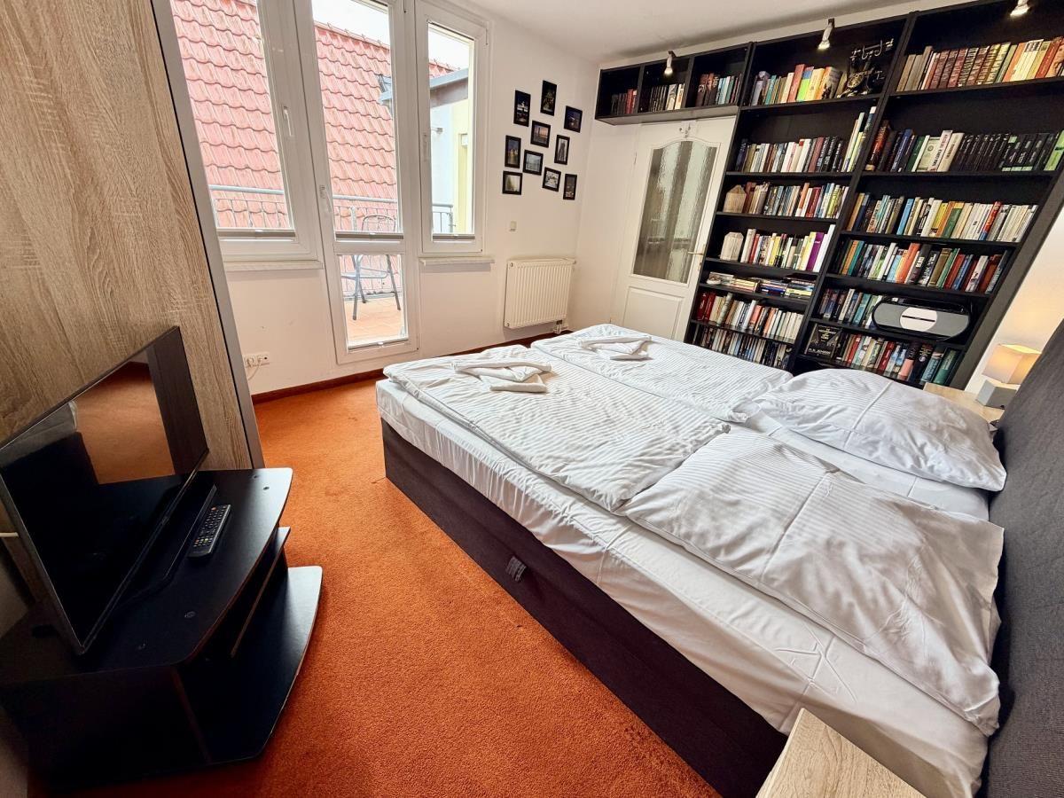 Schlafzimmer mit Bett, Bücherregal und Fenster zum Balkon.