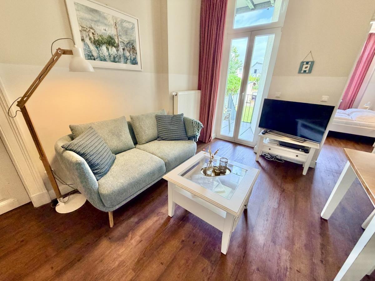 Wohnzimmer mit Sofa, Couchtisch und TV. Durchgang zur Terrasse mit Blick auf Garten.