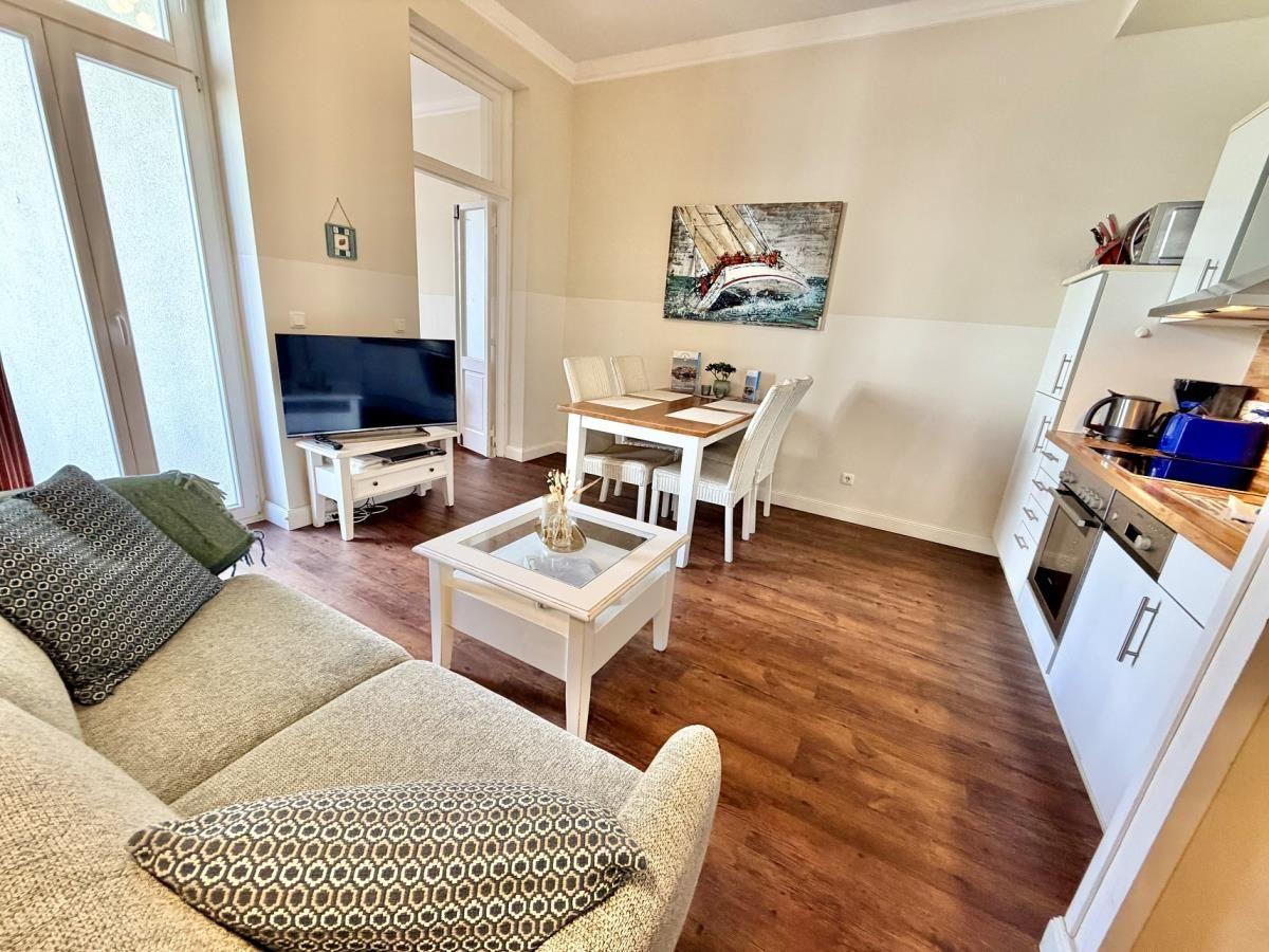 Wohn- und Essbereich mit Sofa, TV, Esstisch und Küche.