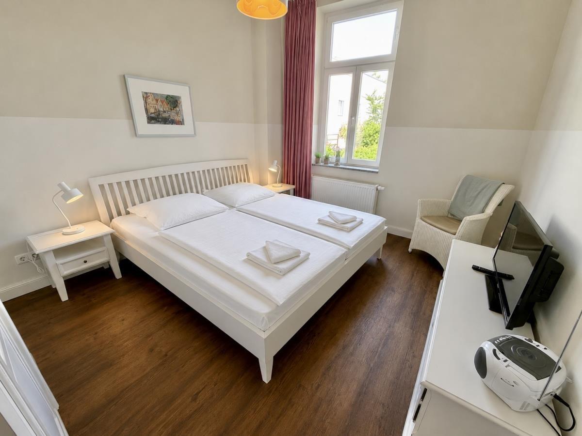 Schlafzimmer mit Doppelbett, Schreibtisch und Fenster mit Blick nach draußen.