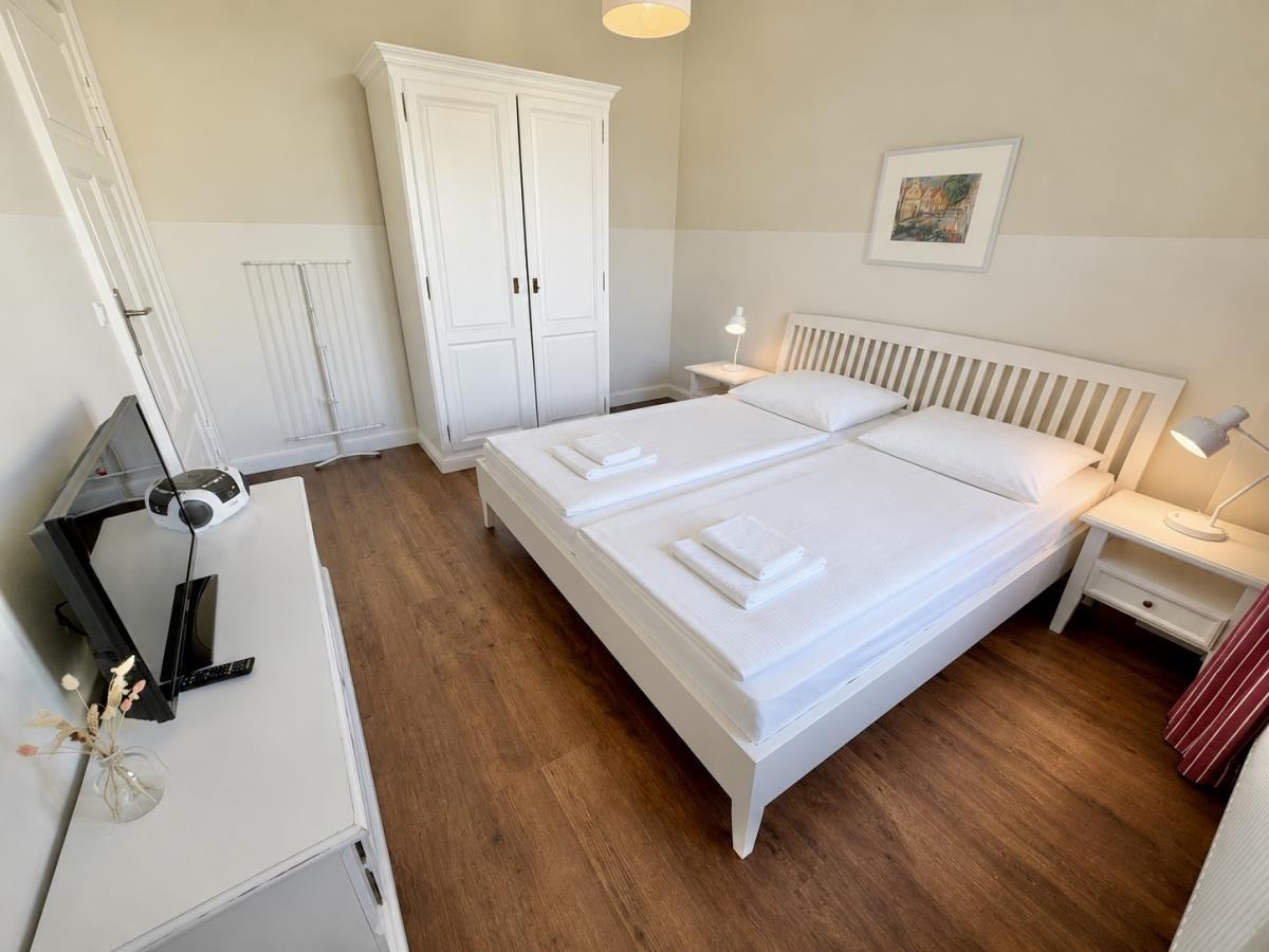Schlafzimmer mit Doppelbett, Kleiderschrank und Nachttischen.