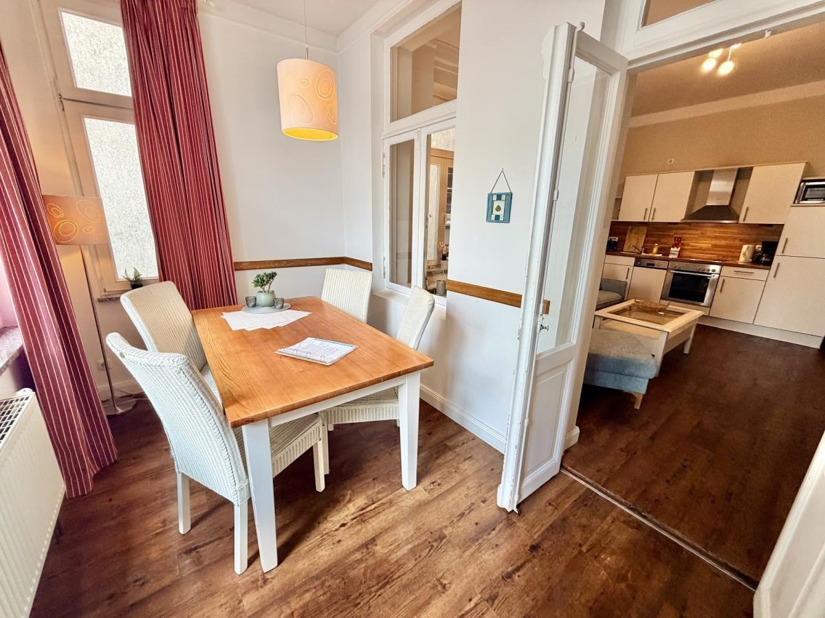 Essbereich mit Holztisch und Stühlen, Küche im Hintergrund.