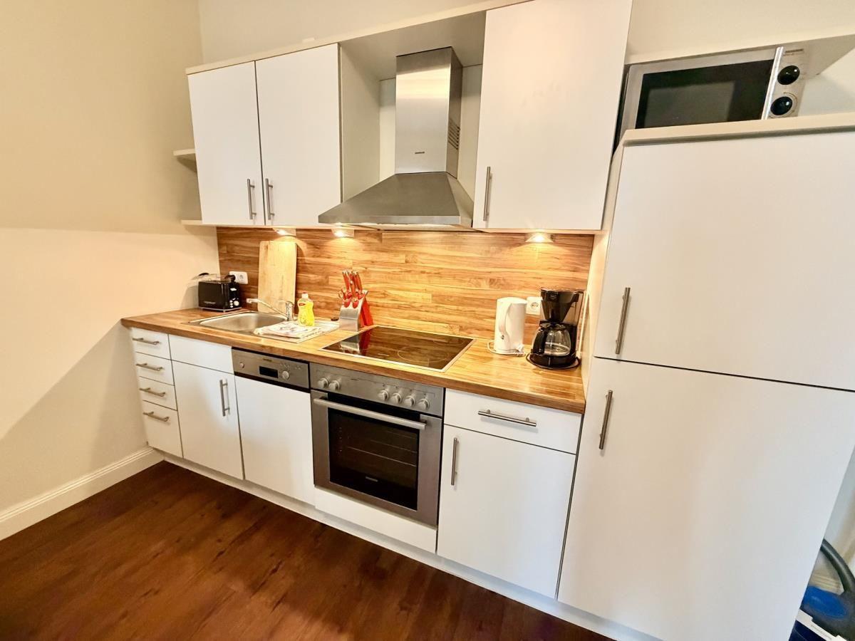 Küche mit weißen Schränken, Holz-Arbeitsplatte und Edelstahlgeräten.