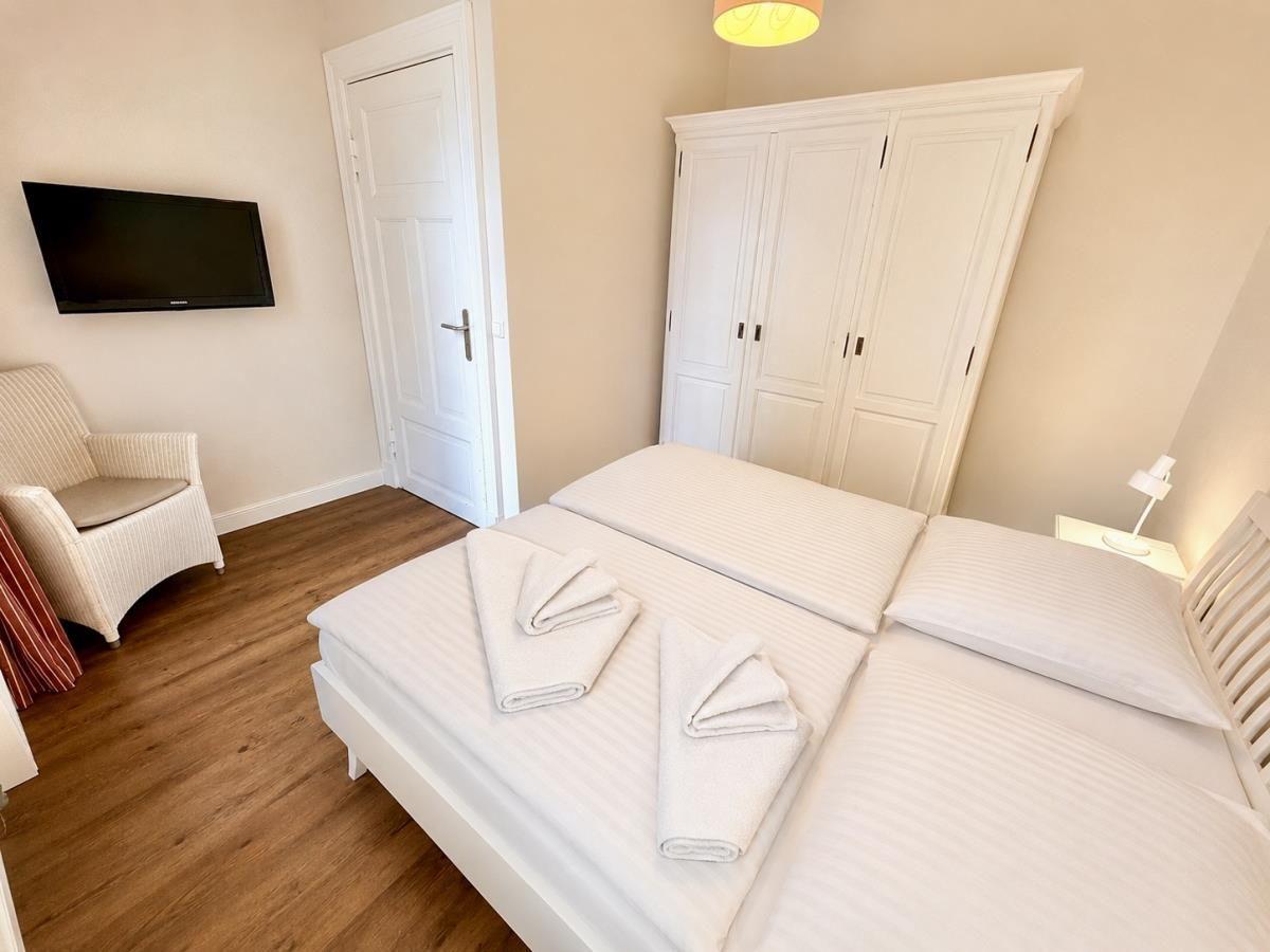 Schlafzimmer mit Doppelbett, Kleiderschrank, TV und Stuhl.