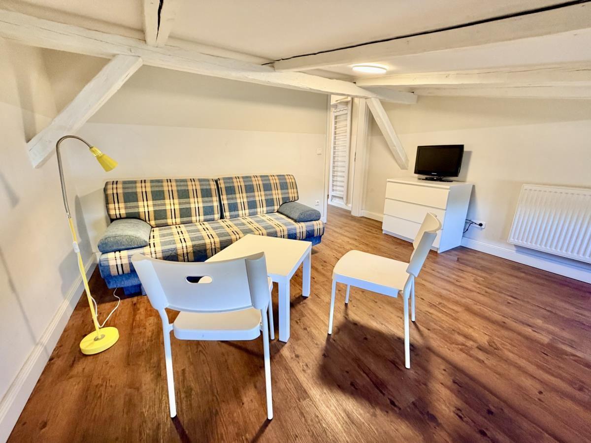 Wohnzimmer mit Sofa, Tisch, Stühlen, Fernseher und Holzboden.