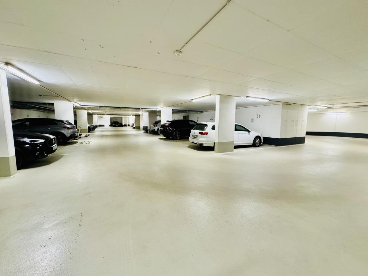 Untertageparkhaus mit mehreren parkenden Autos und Säulen.