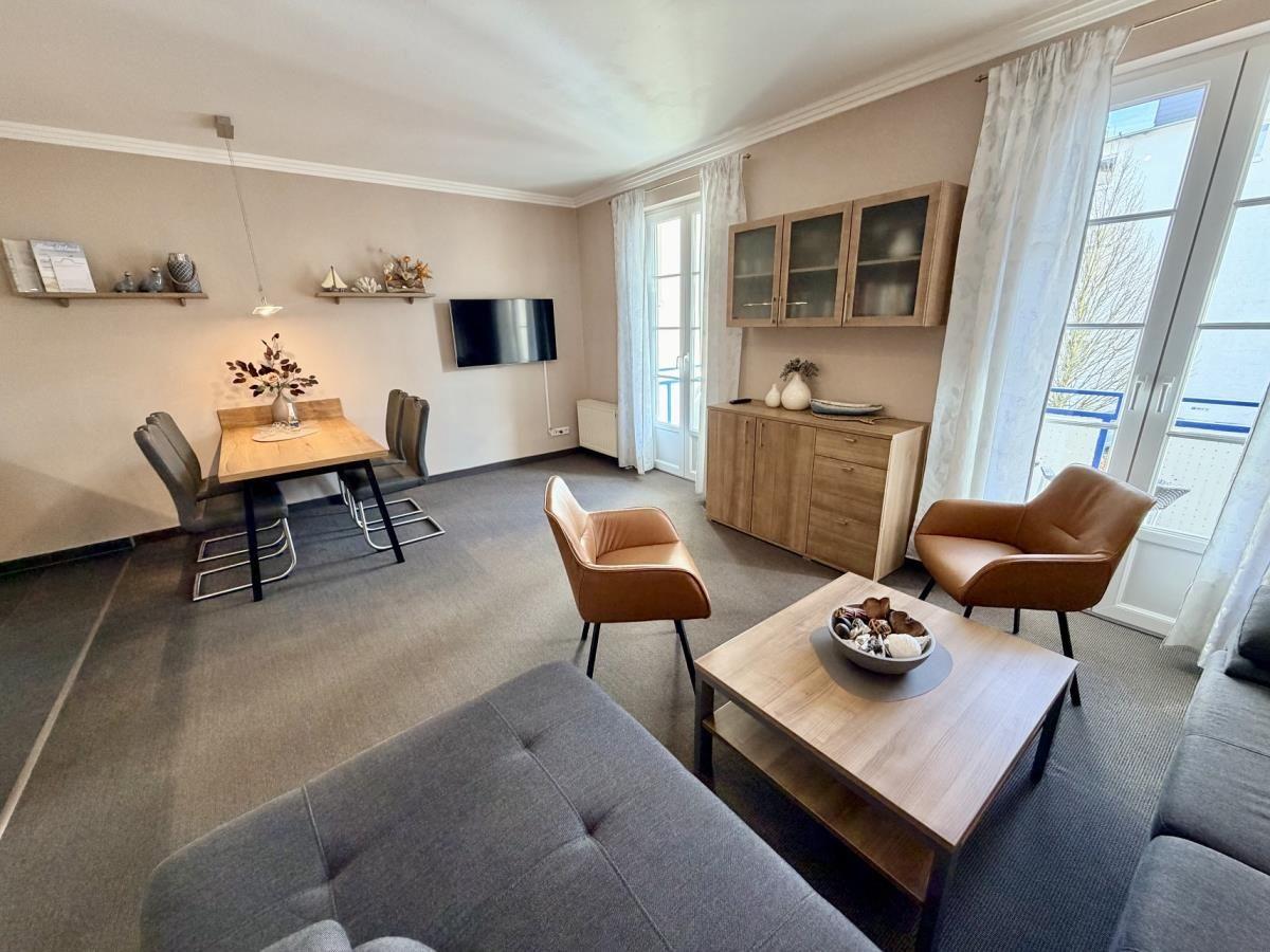 Wohn- und Essbereich mit Sofa, Tisch und Stühlen, Fernseher und Balkontür.