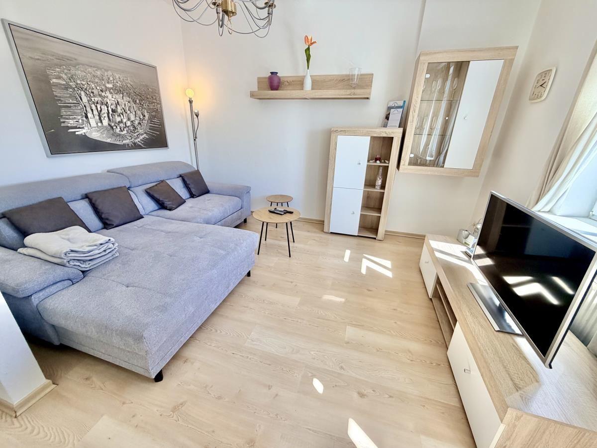 Wohnzimmer mit Sofa, Fernseher und Holzboden.