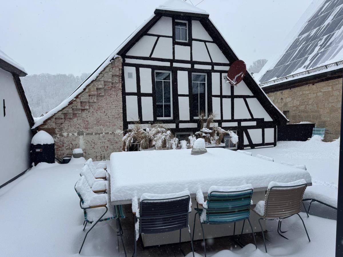 Schneebedeckter Holzhaus-Terrassenbereich mit Tisch und Stühlen.