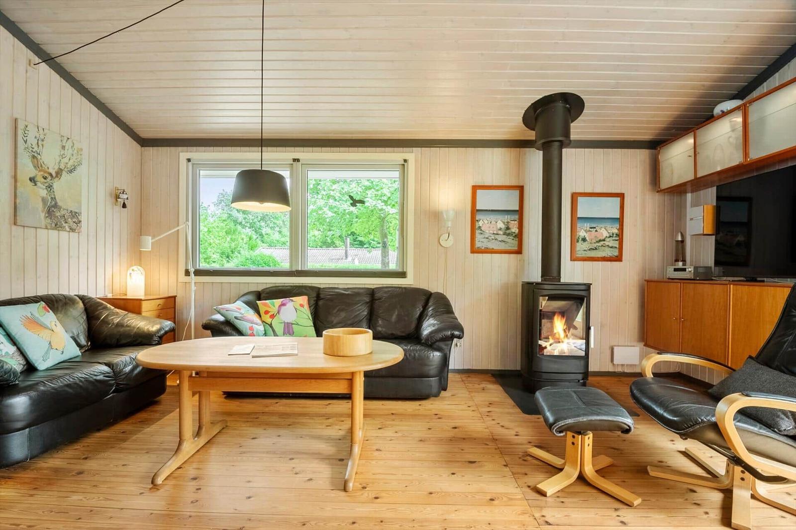 Wohnzimmer mit Holzfußboden, Sofa, Kamin und Fenster zum Garten.