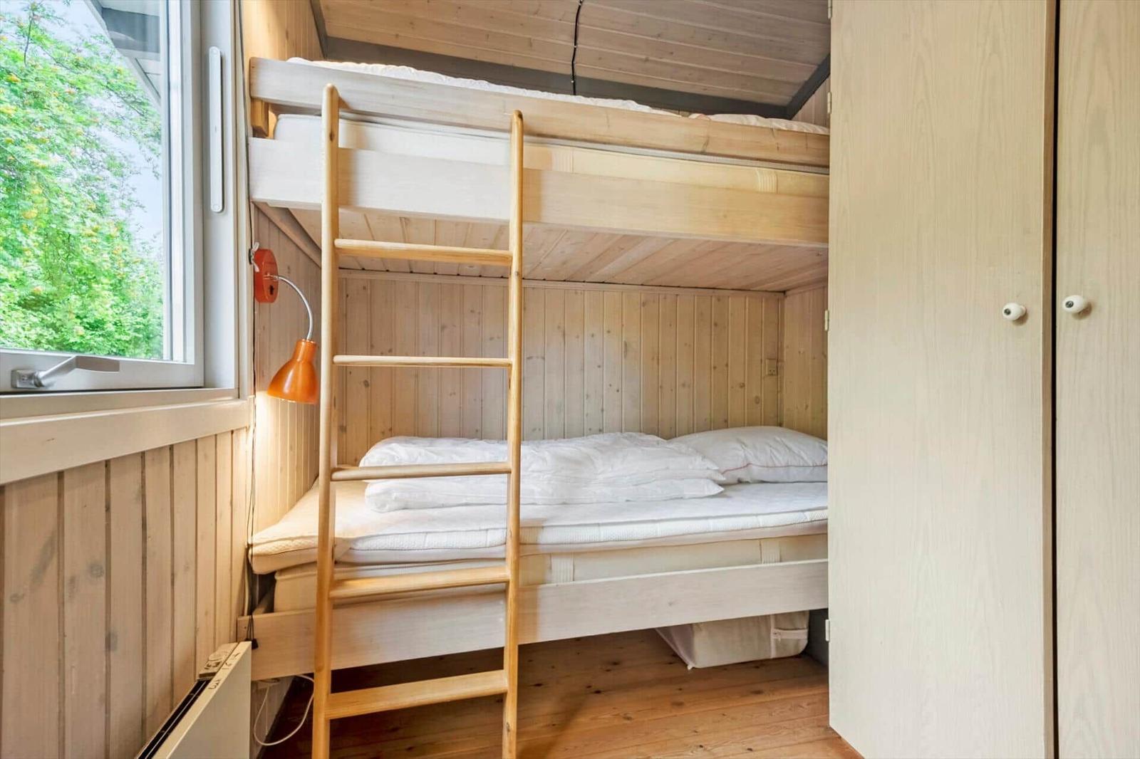 Doppelstockbett mit Holzleiter und Fensterblick auf Bäume