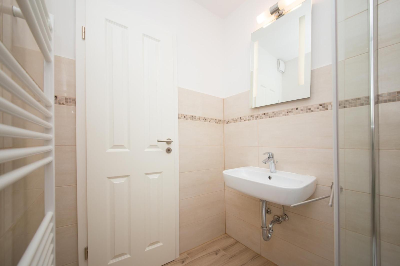 Badezimmer mit Waschbecken, Spiegel und Dusche