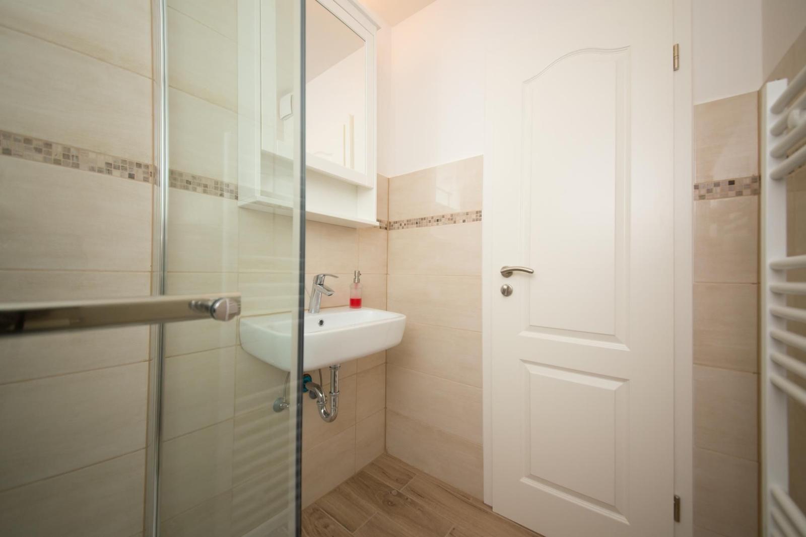 Badezimmer mit Dusche, Waschbecken und Heizkörper