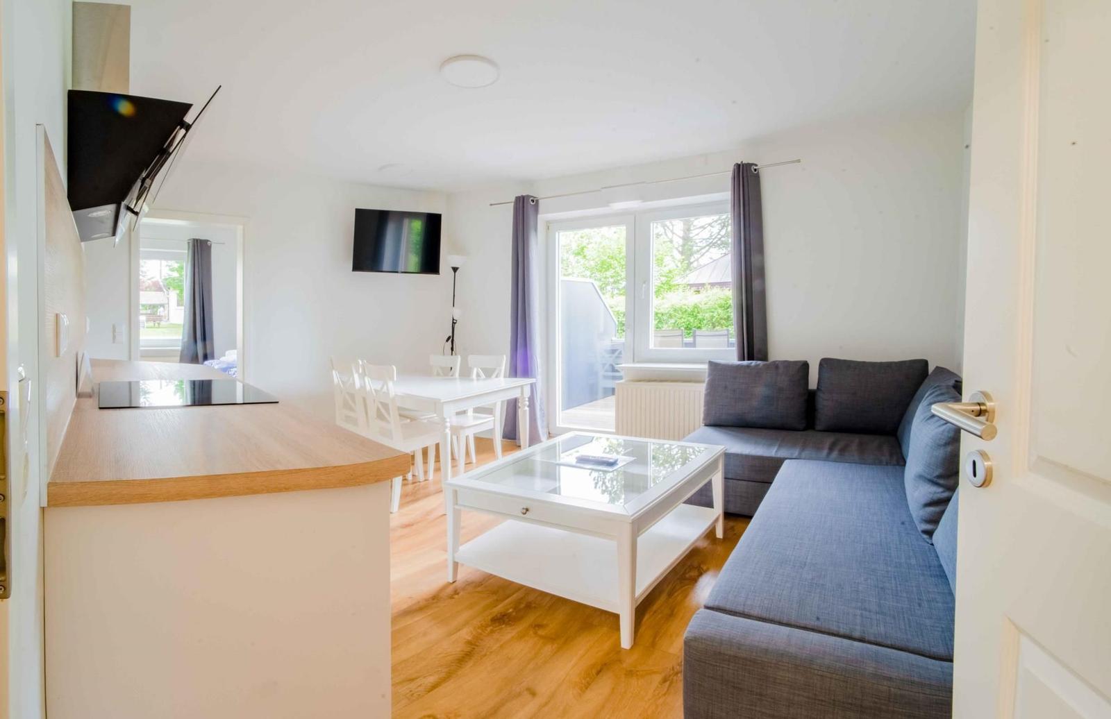 Wohnung mit Kücheninsel, Essbereich und Wohnzimmer mit Sofa und Glas-Tisch.