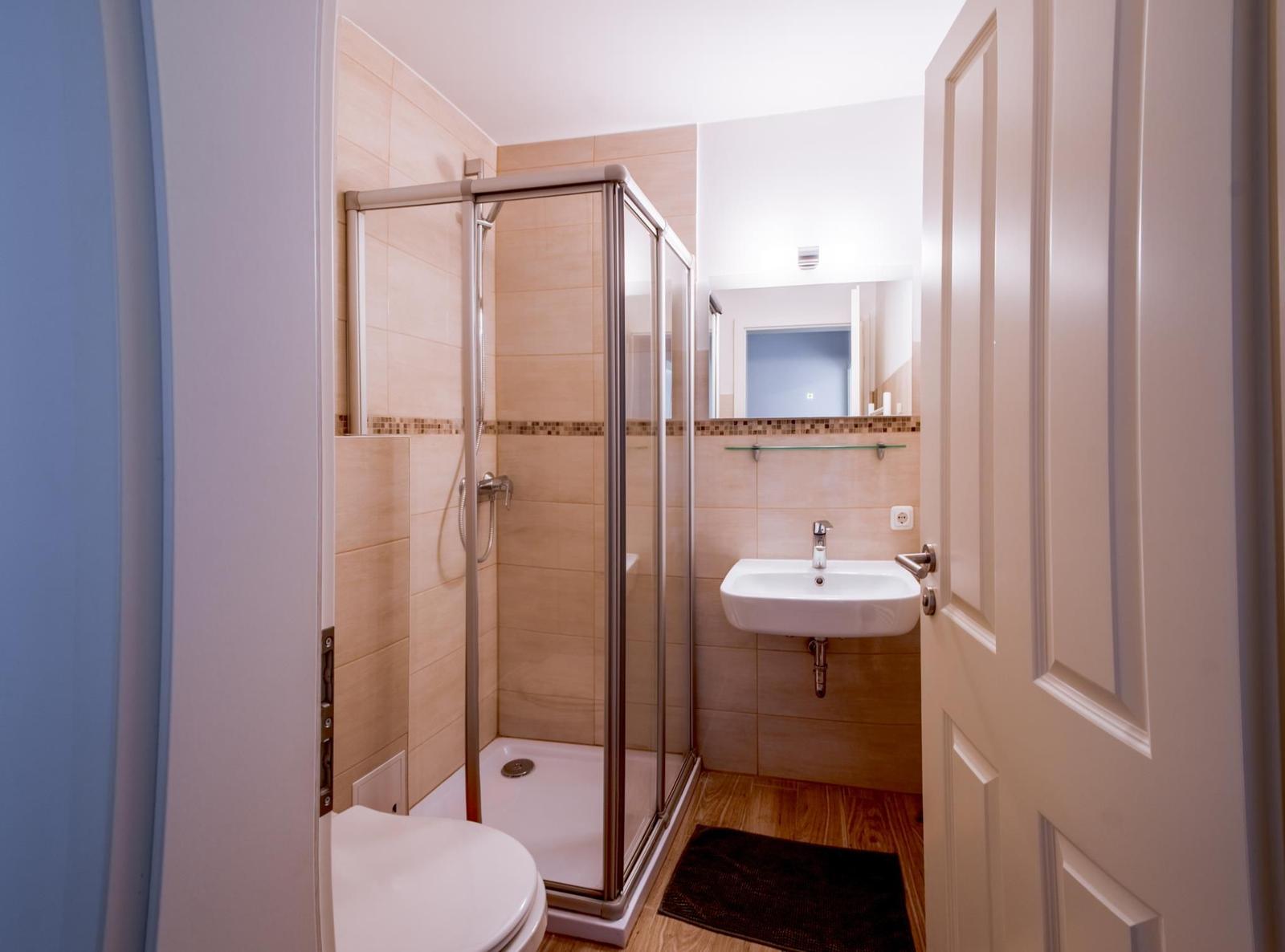 Badezimmer mit Dusche, Waschbecken und Toilette.