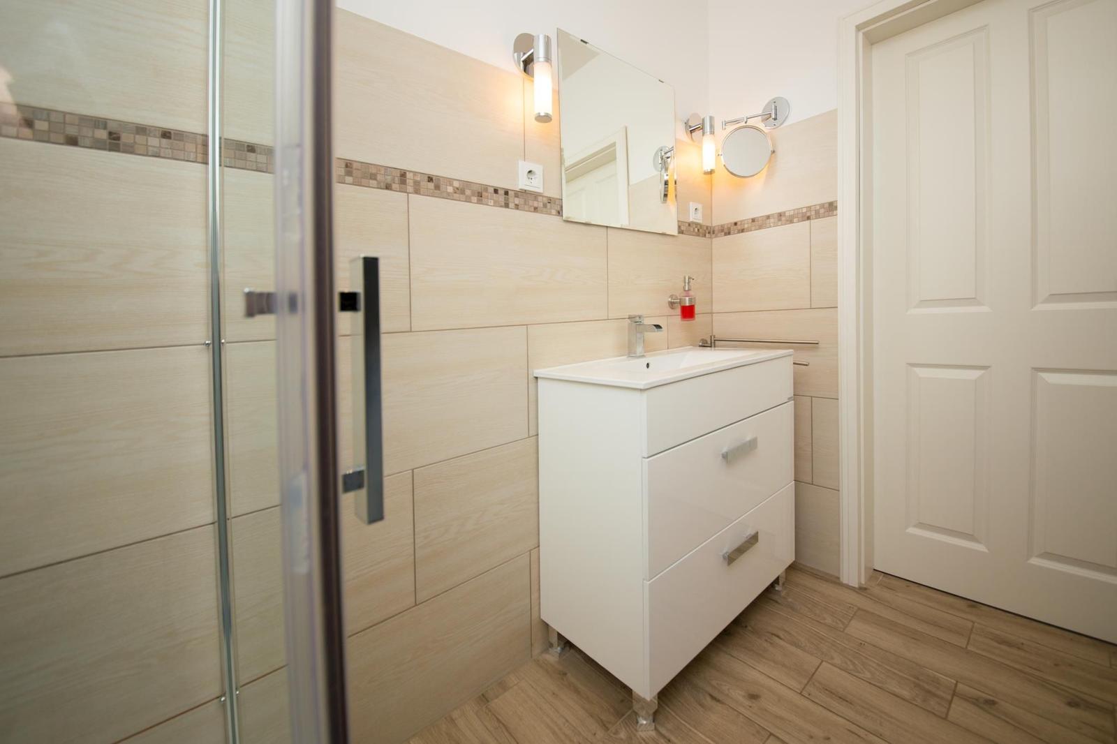 Badezimmer mit Dusche, Waschbecken und Spiegel