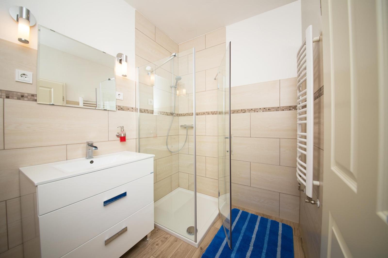 Badezimmer mit Dusche, Waschbecken und Heizkörper