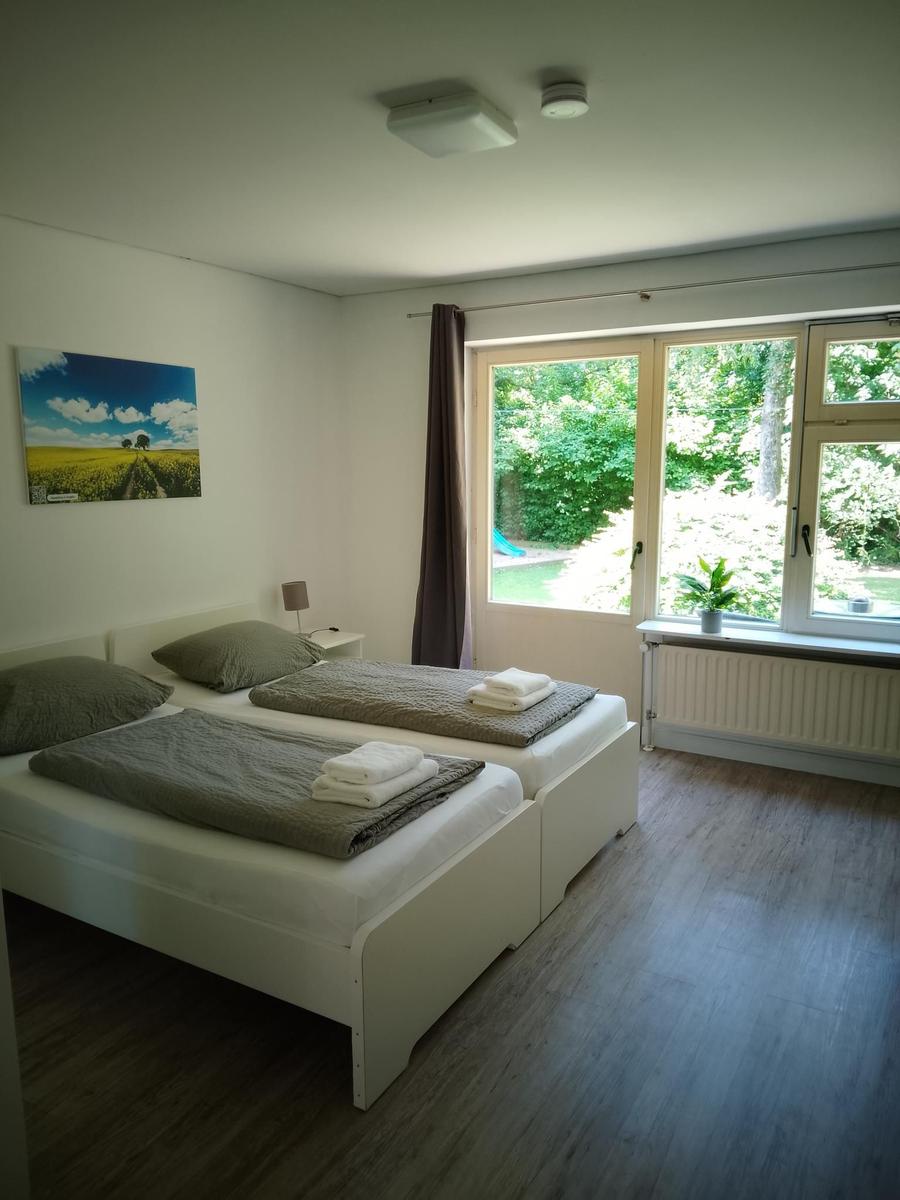 Zwei Schlafplätze mit Bettwäsche, Fenster mit Blick auf Garten.