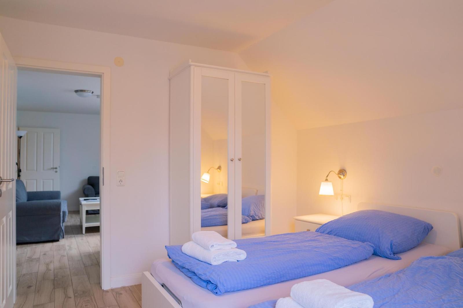 Schlafzimmer mit Bett, Kleiderschrank und Blick in Wohnzimmer