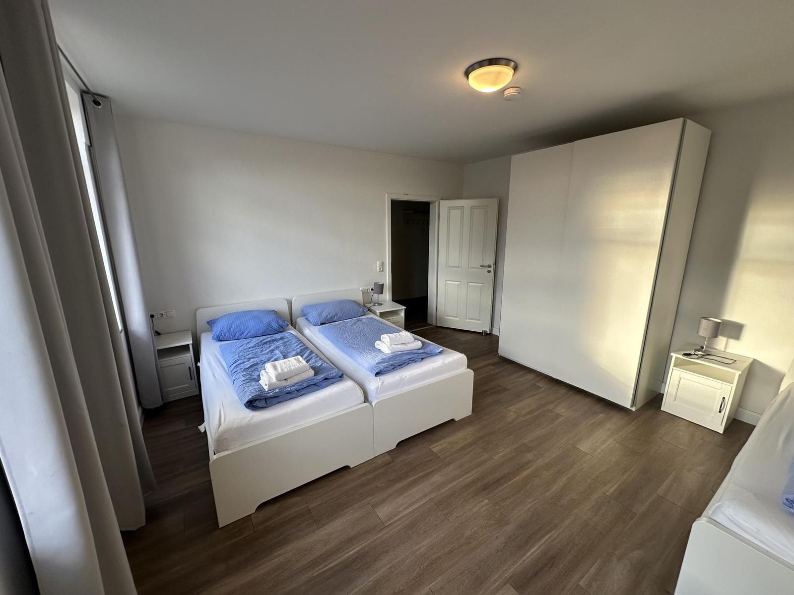 Zimmer mit zwei Betten, Kleiderschrank und Nachttischen.