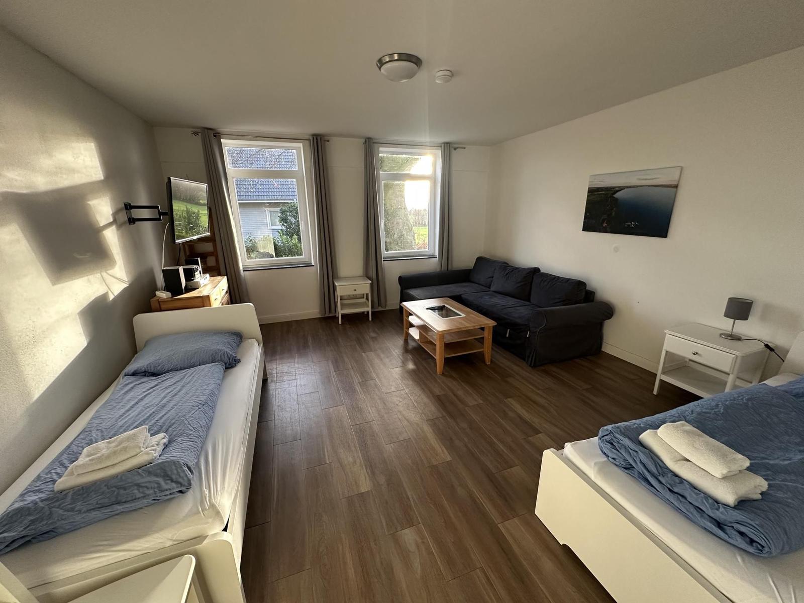 Zwei Betten, Sofa, TV und Fenster mit Blick nach draußen.