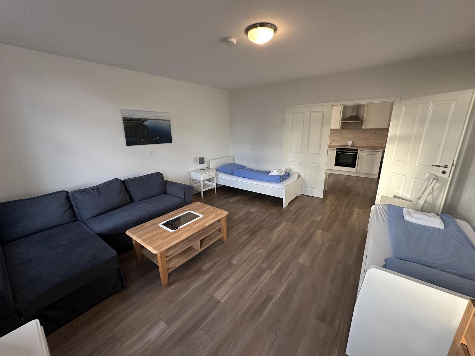 Wohnung mit Sofa, zwei Betten und Küche im Hintergrund.