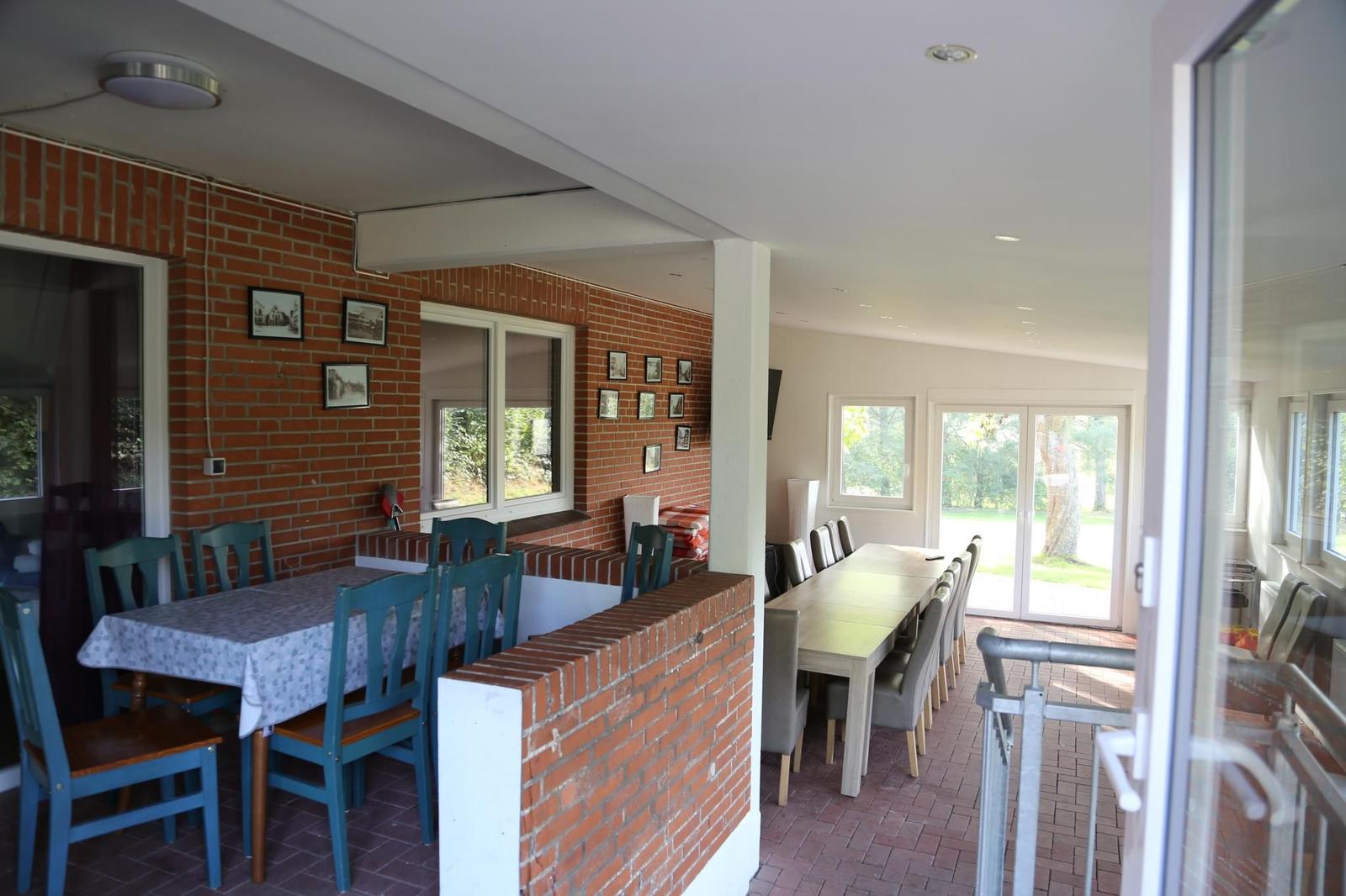 Roter Backsteinwand mit Tisch und Stühlen, Sicht auf Terrasse mit Tisch und Stühlen.