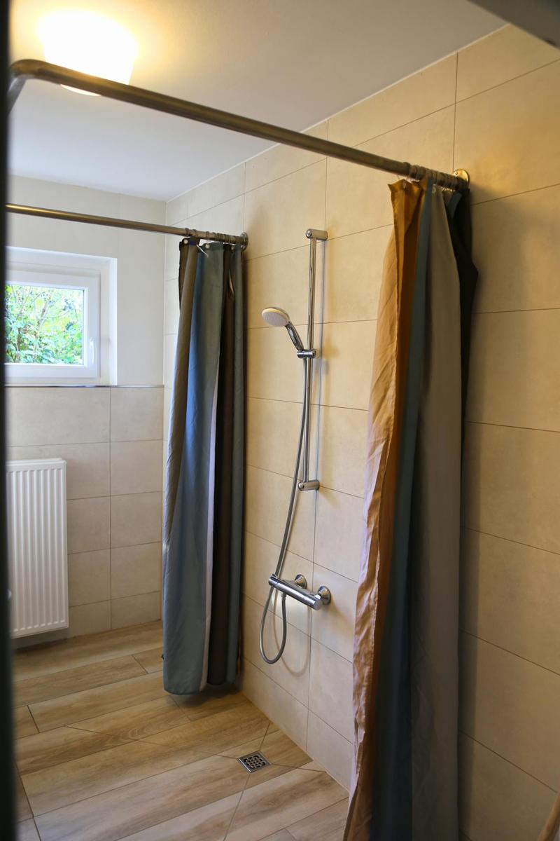 Dusche mit Duschbrause, Fenster und Heizkörper
