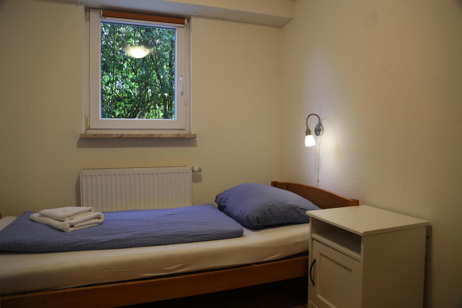 Ein Schlafzimmer mit Bett, Nachttisch und Fenster zum Garten.