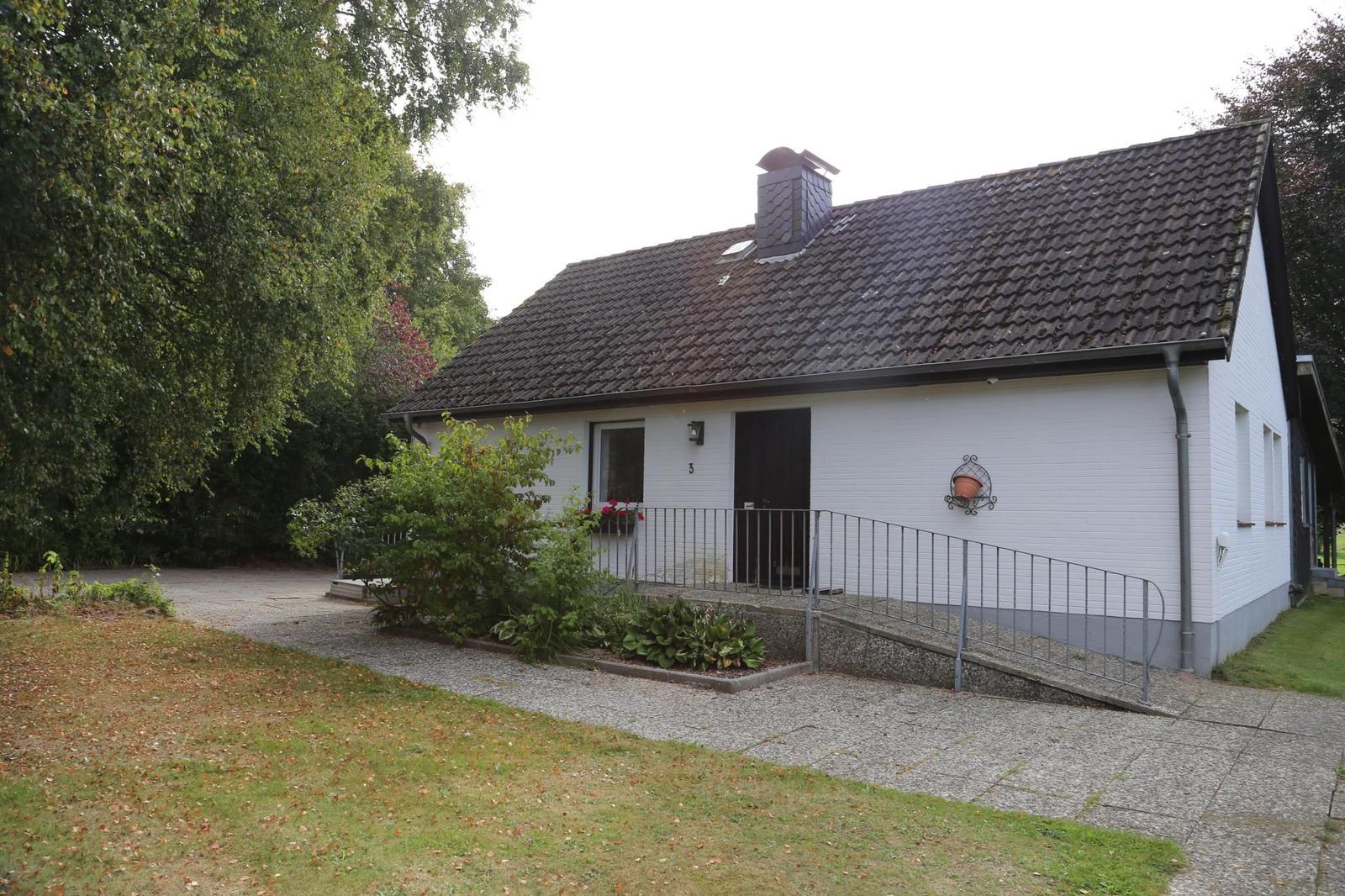 Ein weißes Haus mit dunklem Dach und einer Rampe zur Eingangstür.