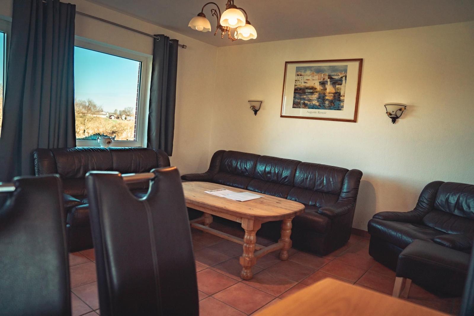 Wohnzimmer mit Ledersofa, Holztisch und Fensterblick