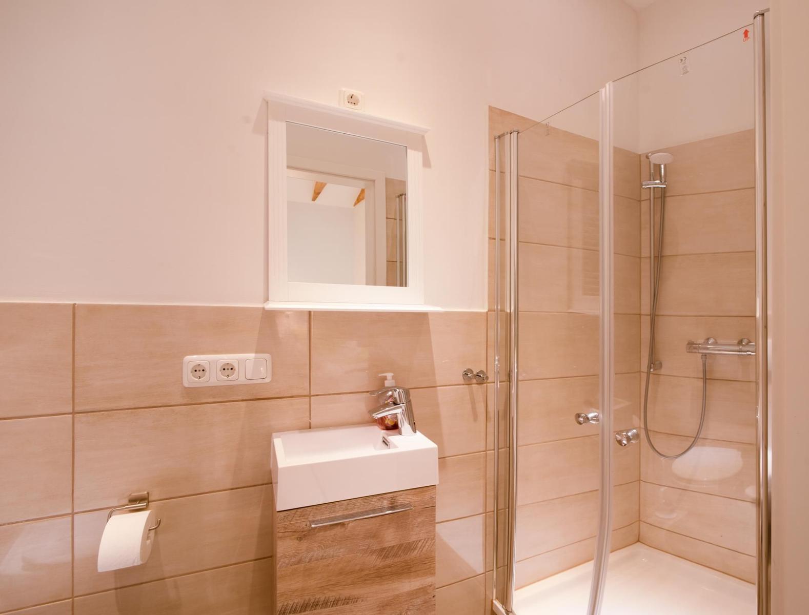 Badezimmer mit Dusche, Waschbecken und Spiegel