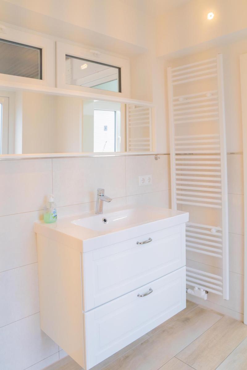 Badezimmer mit Waschbecken, Spiegelschrank und Heizkörper