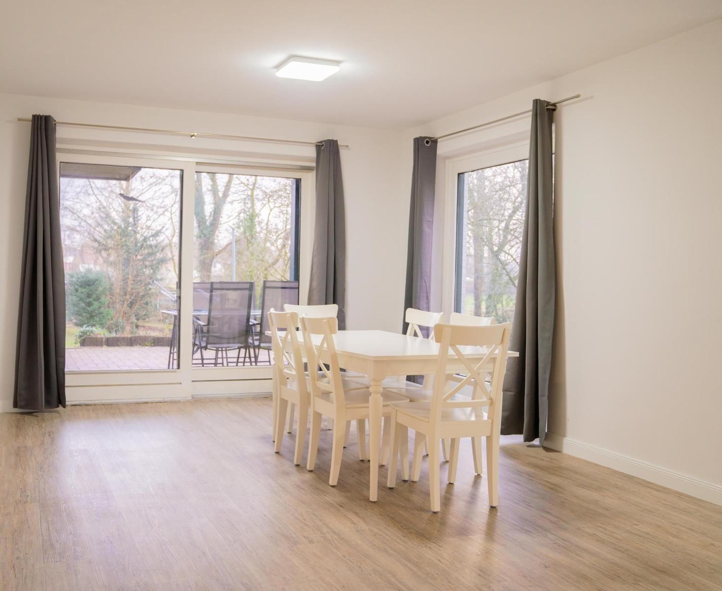 Esszimmer mit Tisch und Stühlen, großes Fenster und Terrasse
