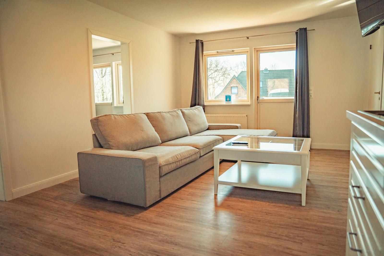 Wohnzimmer mit Sofa, Glas-Tisch und Fenster zur Aussicht.