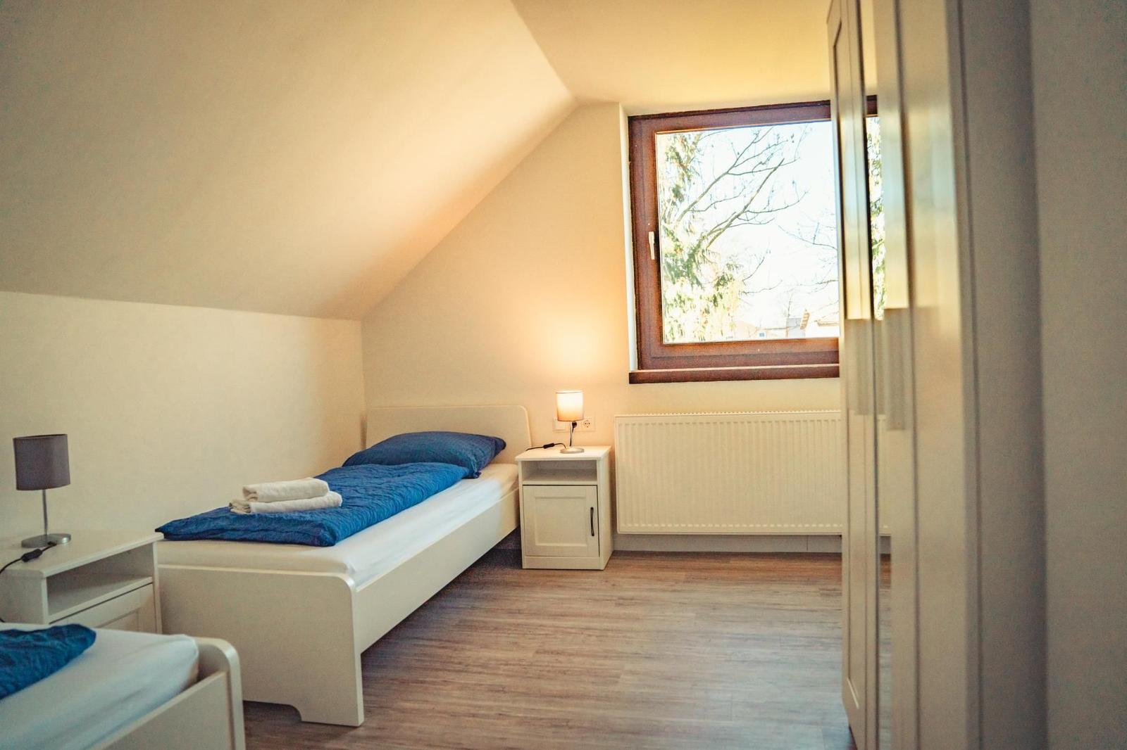 Schlafzimmer mit Dachschräge, Fenster, Bett und Nachttisch.