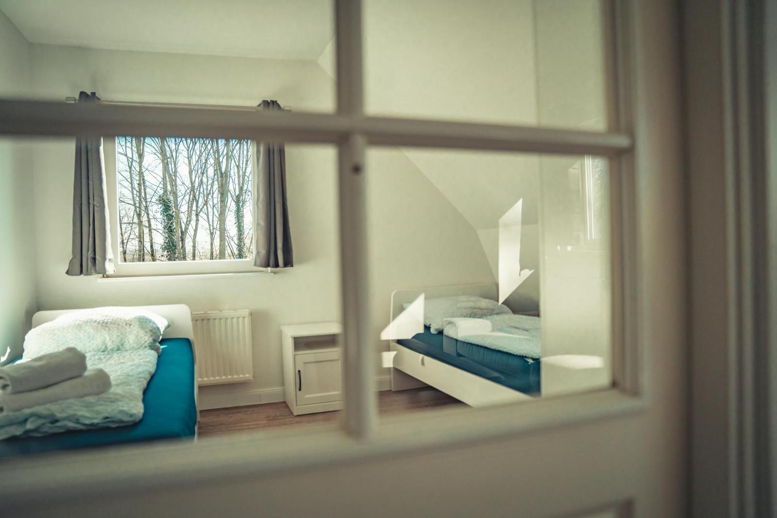 Zimmer mit zwei Betten, Fenster mit Blick auf Bäume und Heizung.