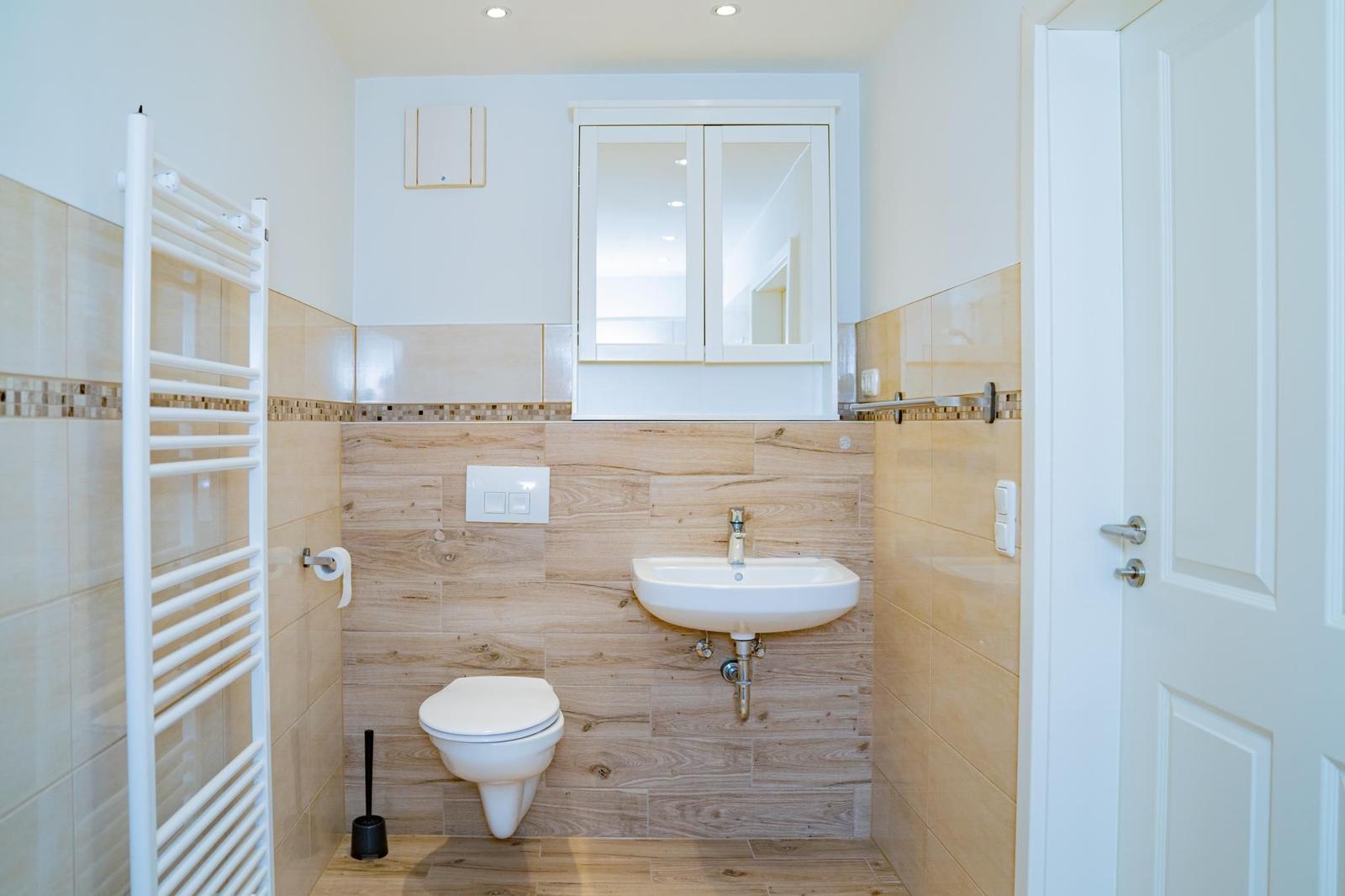 Badezimmer mit Toilette, Waschbecken und Heizkörper an der Wand.