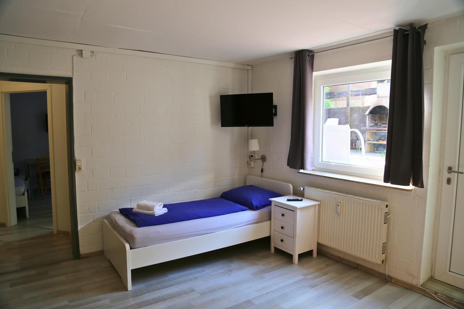 A bedroom with a bed, a dresser, and a TV mounted on the wall.