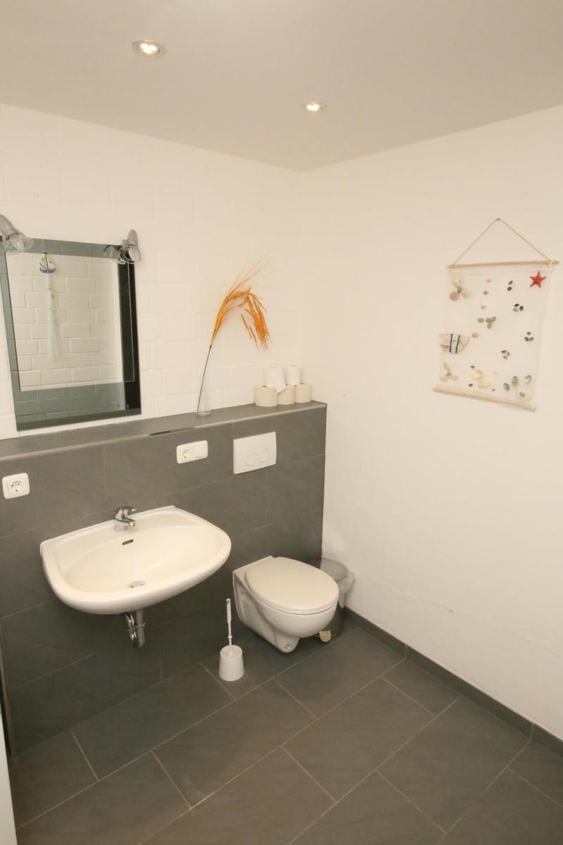 Badezimmer mit Waschbecken, Toilette und Spiegel an der Wand.