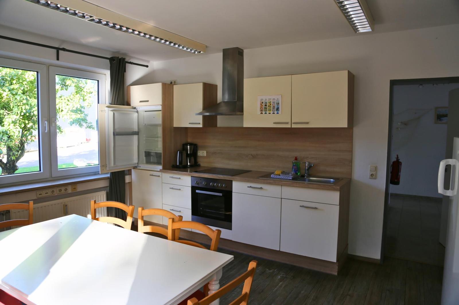Küche mit Essbereich, Kühlschrank, Herd und Fenster mit Blick nach draußen.