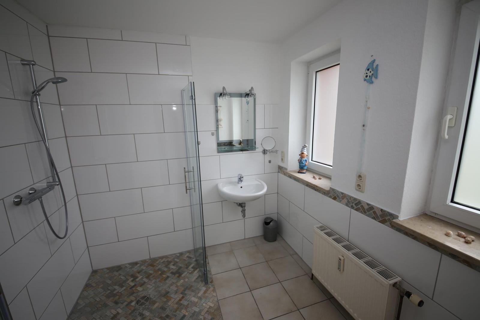 Badezimmer mit Dusche, Waschbecken und Fenster